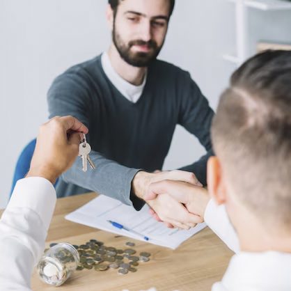 Cliente estrechando la mano y agente mirando las llaves